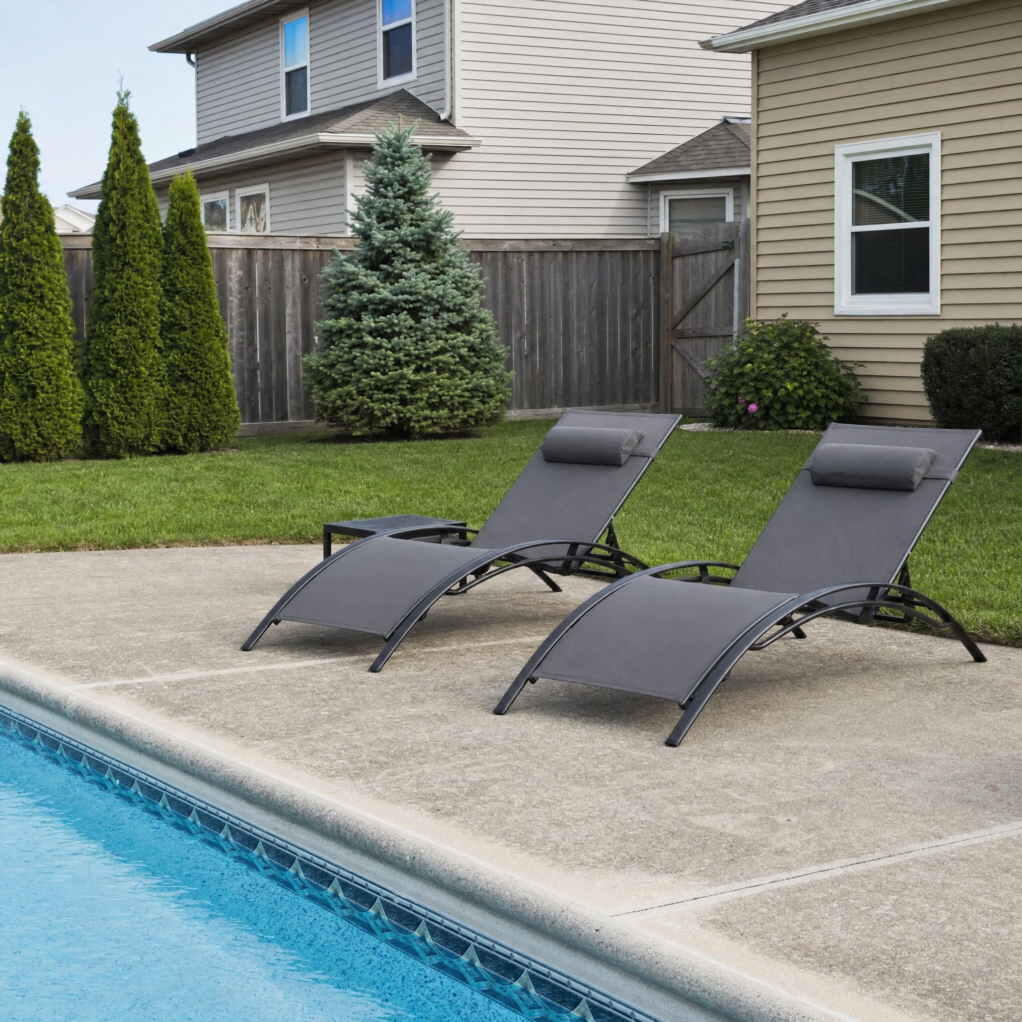 Two black-frame grey-mesh chaise loungers with side table by pool