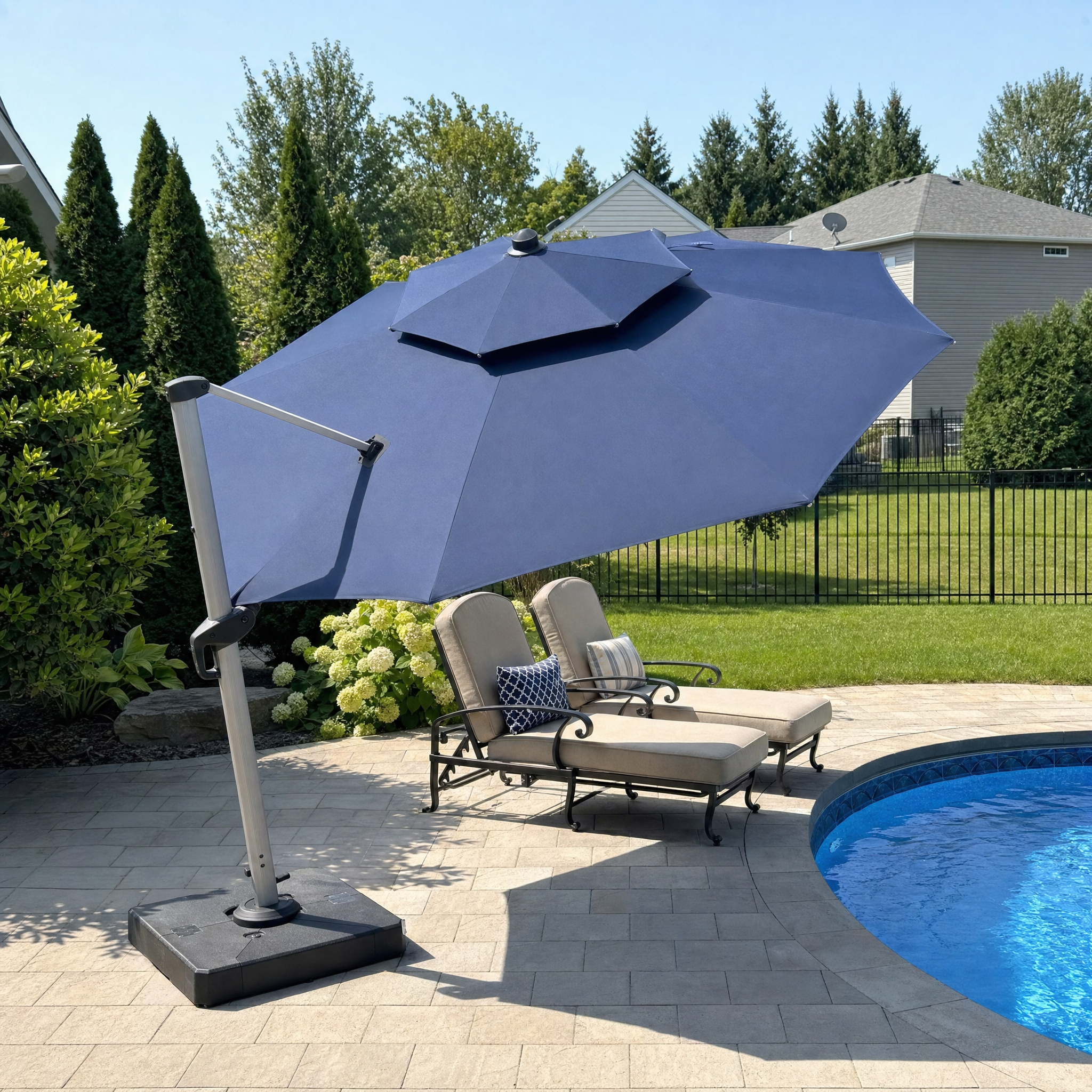 Round navy cantilever patio umbrella beside an in-ground pool on a paver deck