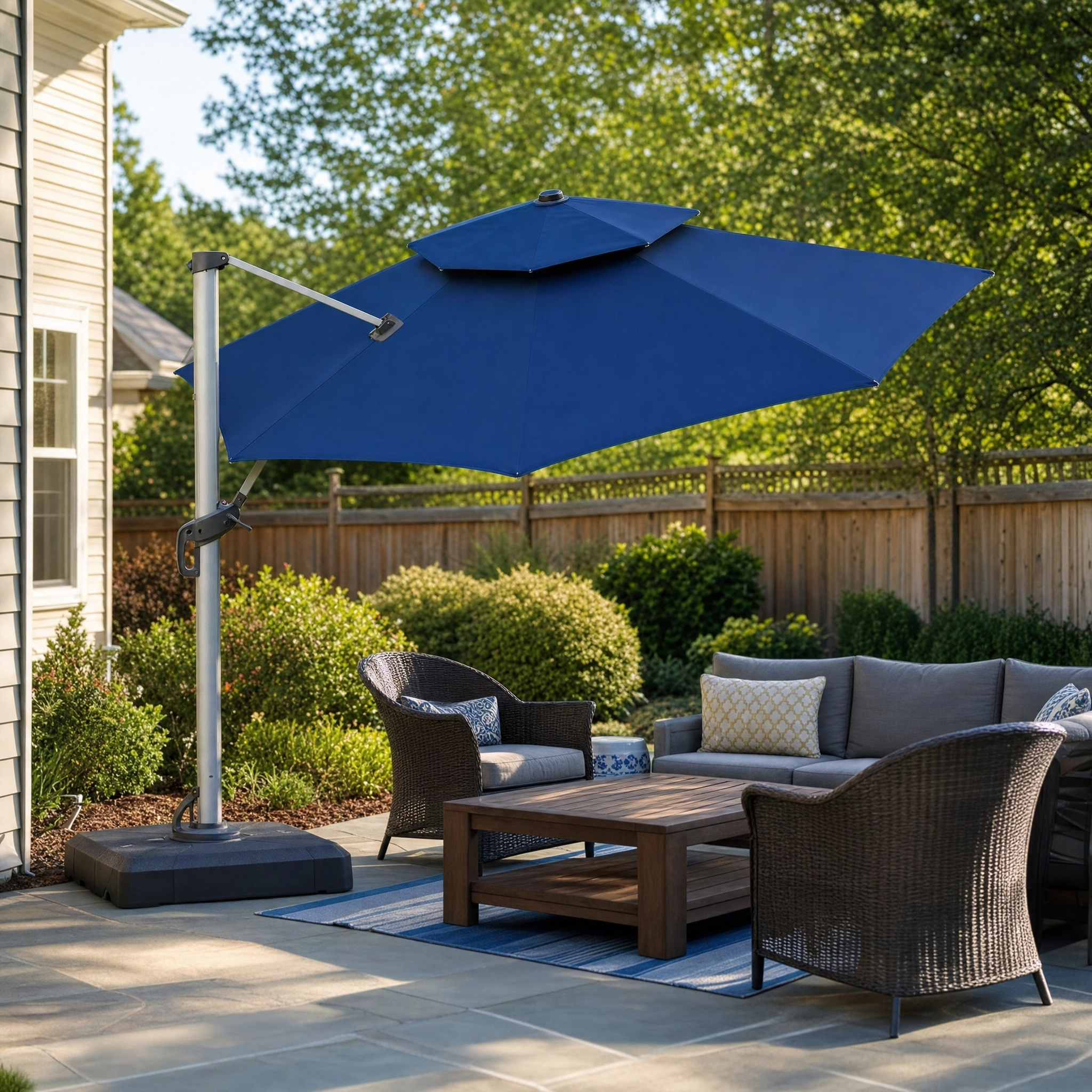 Round navy cantilever patio umbrella over a wicker lounge seating set on a backyard patio