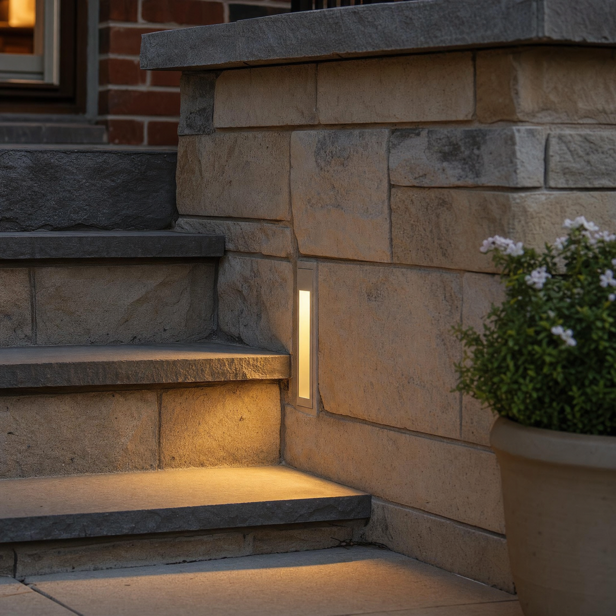 Recessed LED stairway step light glowing warm in a stone step wall at dusk