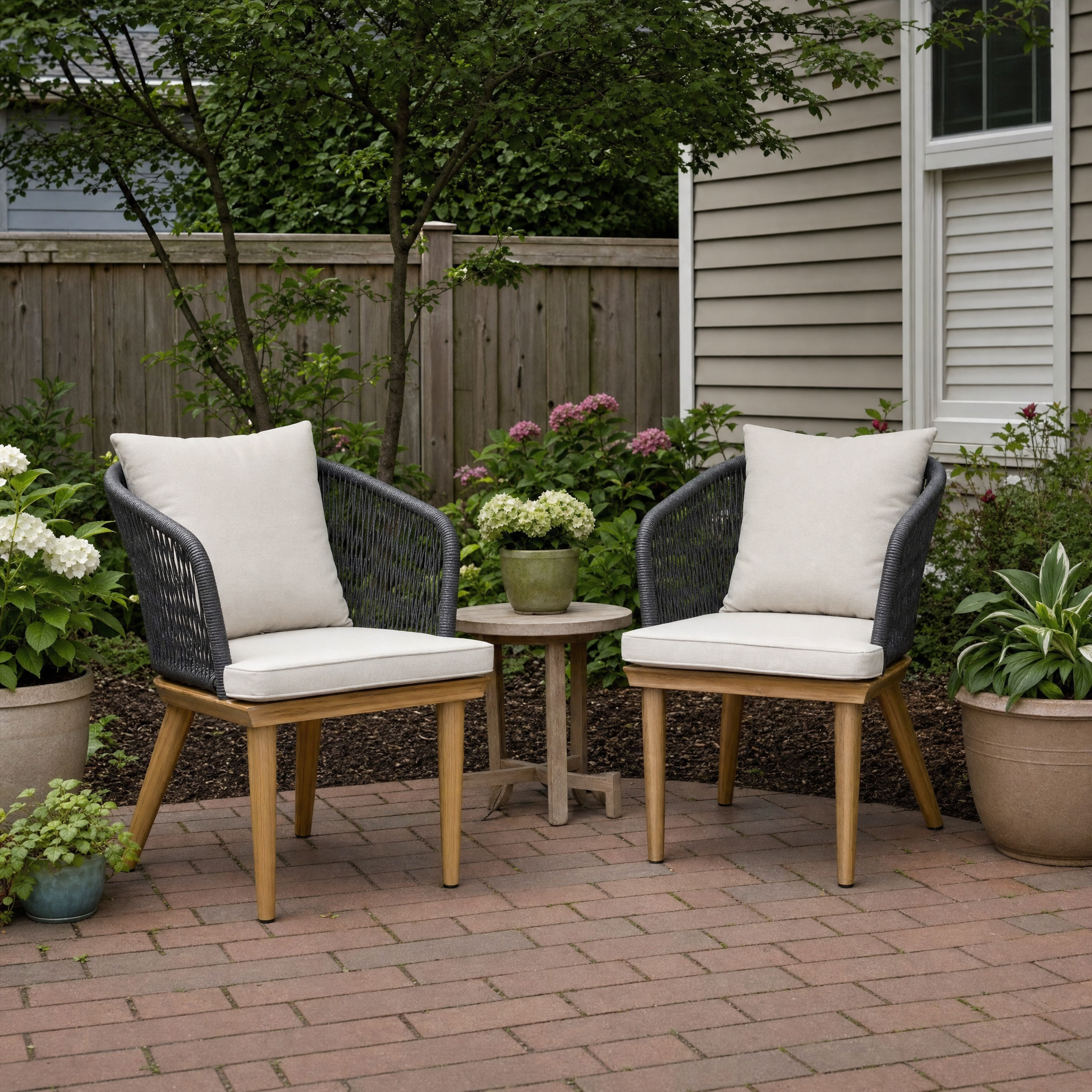 Two grey rope-back bistro chairs with wood legs, cream cushions and side table